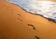 bigstock-beach-wave-and-footsteps-at-s-38822107resized